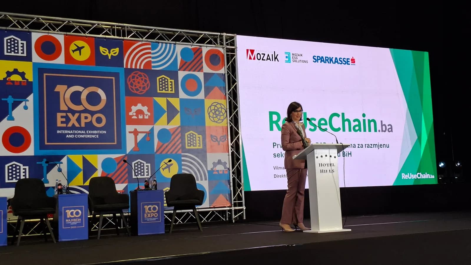 Govornica za govornicom na pozornici 100 EXPO uz projekciju ReUseChain.ba.