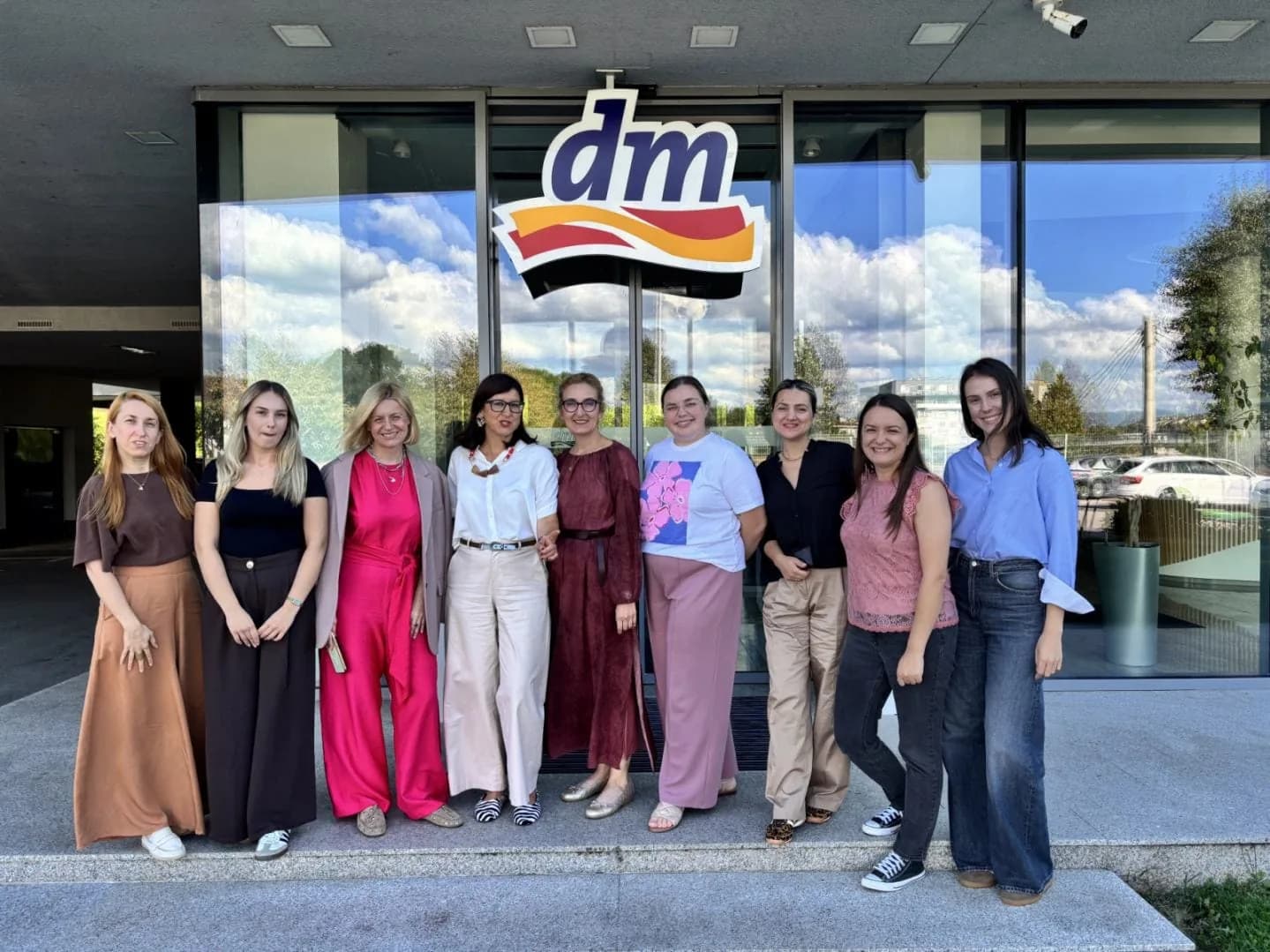 Grupna fotografija učesnica inicijative „Žar za budućnost“ ispred zgrade s dm logotipom.
